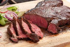 A picture of a delicious steak. There are some veggies there but they are not important.